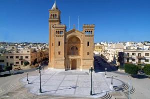 un grand bâtiment avec une tour d'horloge dans une ville dans l'établissement Caris Gem, à Birżebbuġa