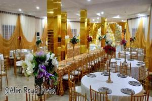 a banquet hall with white tables and chairs and flowers at Alim Royal Hotel in Jahi