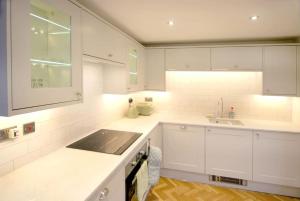 una cocina blanca con armarios blancos y fregadero en Beautiful barn conversion with easy access to York, en Selby