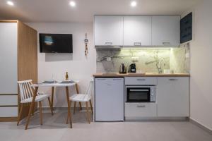uma cozinha com armários brancos e uma pequena mesa em ALMIRA Studios Limnos 3 em Myrina