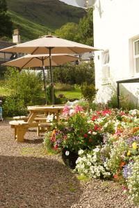a picnic table and umbrella in a garden with flowers at Clachan Garden B&B in Garve