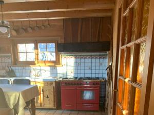 a kitchen with a red stove top oven next to a table at Chalet Luxe Les Orchis Alpe d'Huez in LʼHuez