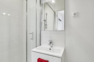 La salle de bains blanche est pourvue d'un lavabo et d'une douche. dans l'établissement T2 4 pers Wifi limite Vincennes et métro E1, à Montreuil