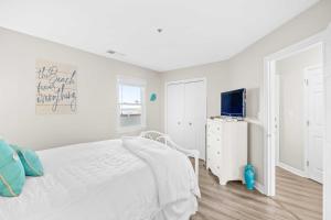 ein weißes Schlafzimmer mit einem Bett und einem TV in der Unterkunft Villa Capriani Condo with Direct Beach Access! in North Topsail Beach