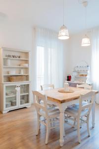 una sala da pranzo bianca con tavolo e sedie in legno di Residenza Porta Palio a Verona