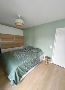 Schlafzimmer mit einem grünen Bett und Holzboden in der Unterkunft Bel appartement lumineux résidentiel proche de Paris in Ivry-sur-Seine