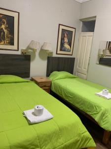 twee groene bedden in een kamer met groene lakens bij Posada Casa Real in Huancayo