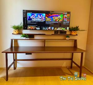 a wooden table with a tv on a wall at Super Luxurious Stay at Biggest Mall Galaxy Blue Sapphire,Bar, Club, US Cinemas, Food Court, SuperMart etc, by Taj Studios in Ghaziabad