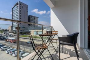uma varanda com duas cadeiras e uma mesa e uma cidade em Harbor 203 Stylish 1-Bedroom Apartment in Larnaca em Lárnaca