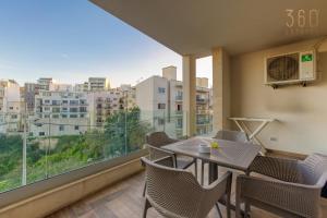 uma varanda com uma mesa e cadeiras e uma grande janela em Luxury 3BR home in St Julians with private terrace by 360 Estates em Taʼ Ċikkun