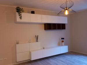 una cucina con armadietti bianchi e lampadario; di La casa di Tina - Civenna a Civenna