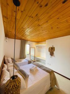 Un dormitorio con dos camas y techo de madera. en Casa Saíra, a 300 metros da praia do Patacho, Porto de Pedras-AL, en Porto de Pedras