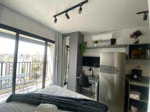 a bedroom with a refrigerator and a desk with a balcony at Apartamento ao lado metrô Vl. Mariana in Sao Paulo