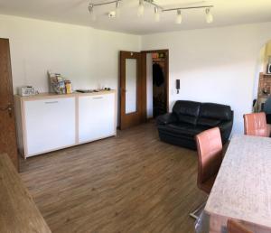 a living room with a black leather couch and a kitchen at Ferienwohnung Seeglück 