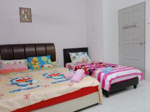 dos camas sentadas una al lado de la otra en un dormitorio en Homestay Bukit Katil Melaka, en Melaka