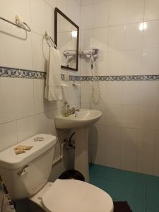 a white bathroom with a toilet and a sink at Posada J in Baños