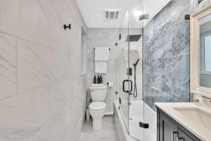 a white bathroom with a toilet and a sink at Walkabout 3 King Suite on the Ocean in Hollywood Beach in Hollywood