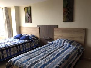 duas camas sentadas uma ao lado da outra num quarto em Apartamento completo en el centro de Ipiales em Ipiales