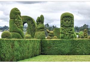 a green garden with some statues in the grass at Apartamento completo en el centro de Ipiales in Ipiales
