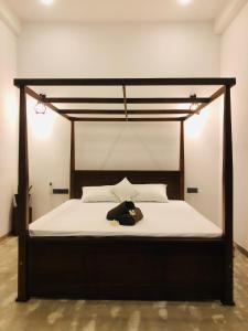 a bed with a wooden frame and white sheets at Simplex Sea Place in Tangalle