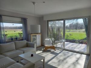 a living room with a couch and a large sliding glass door at Ferienhaus Dat Landhuus 95158 in Rhauderfehn