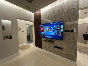 TV en una pared de piedra en una habitación en شقة فاخرة غرفتين نوم ودخول ذاتي, en Riad