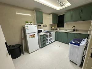 cocina con armarios verdes y nevera blanca en شقة فاخرة غرفتين نوم ودخول ذاتي, en Riad
