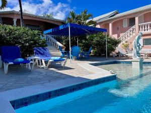 a swimming pool with chairs and an umbrella next to a house at Sun Caraibes in Orient Bay