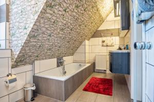 La salle de bains est pourvue d'une baignoire et d'un tapis rouge. dans l'établissement Ferienwohnung Dornhege, à Borken