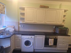 eine Küche mit einer Waschmaschine und einem Waschbecken in der Unterkunft NB's Cozy Nook in Shevington