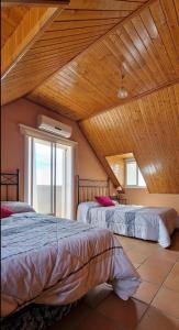two beds in a room with a wooden ceiling at Casa en el corazón de Córdoba in Montoro