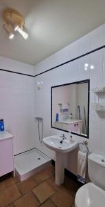 een badkamer met een wastafel, een toilet en een spiegel bij Casa en el corazón de Córdoba in Montoro