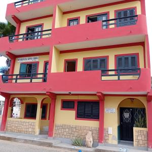 un edificio rojo y amarillo con ventanas negras en Residencial Rosa Criola, en Sal Rei