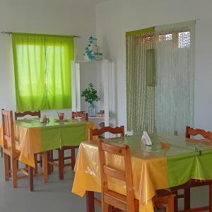 a dining room with two tables with yellow and green covers at Residencial Rosa Criola in Sal Rei