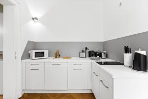 a white kitchen with white cabinets and a microwave at limehome Dresden Antonstraße in Dresden