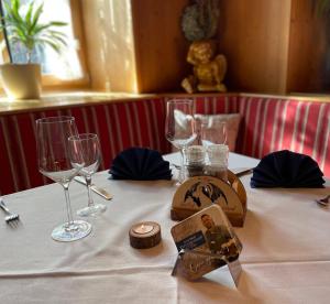 a table with wine glasses and a plate on it at Gasthof Herzogstand bei Stefan in Benediktbeuern