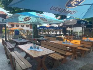 a restaurant with wooden tables and blue umbrellas at Gasthof Herzogstand bei Stefan in Benediktbeuern