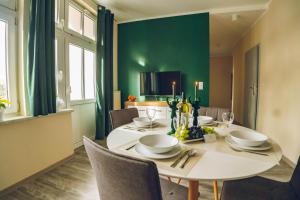 a dining room with a white table and green wall at Apartamenty ABRACADABRA in Ustroń