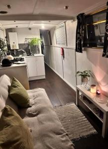 a living room with a couch and a kitchen at Narrow Boat moored in London in London