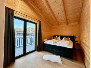 a bedroom with a bed and a large window at Clofers Nature Chalets Obermöschach in Hermagor