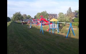 a playground in a grassy field with a park at Chalet Olive im Park De Veerstal in Lathum