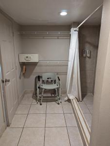 une chaise assise dans une pièce avec douche dans l'établissement Hotel Monte Carlo, à Kissimmee