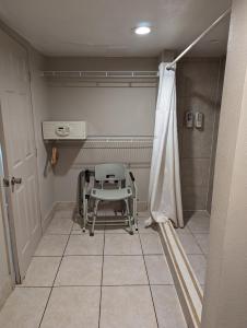 a chair sitting in a room with a shower at Hotel Monte Carlo in Kissimmee