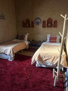 1 dormitorio con 2 camas y alfombra roja en hostels Planet Sahara, en Merzouga