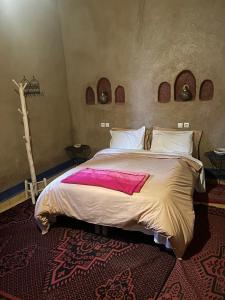 a bedroom with a large bed with pink sheets at kasbah Planet Sahara in Merzouga