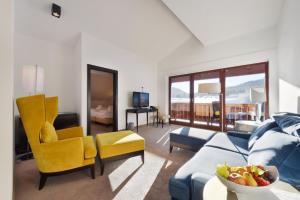 a living room with a blue couch and yellow chairs at Mountains Hotel in Seefeld in Tirol
