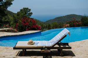 un cappello seduto su una chaise longue accanto alla piscina di Paissa d'en Bernat a Cala Tarida