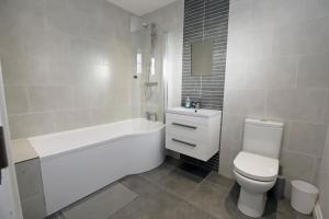 y baño blanco con aseo, bañera y lavamanos. en Royal Hillsborough Village Luxury Townhouse, en Hillsborough