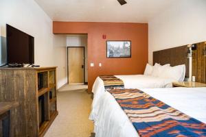 a hotel room with two beds and a flat screen tv at Grand Cloudcroft Hotel in Cloudcroft