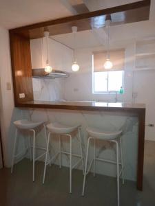 a kitchen with three stools and a counter with a mirror at Casita de Zacate in Cagayan de Oro